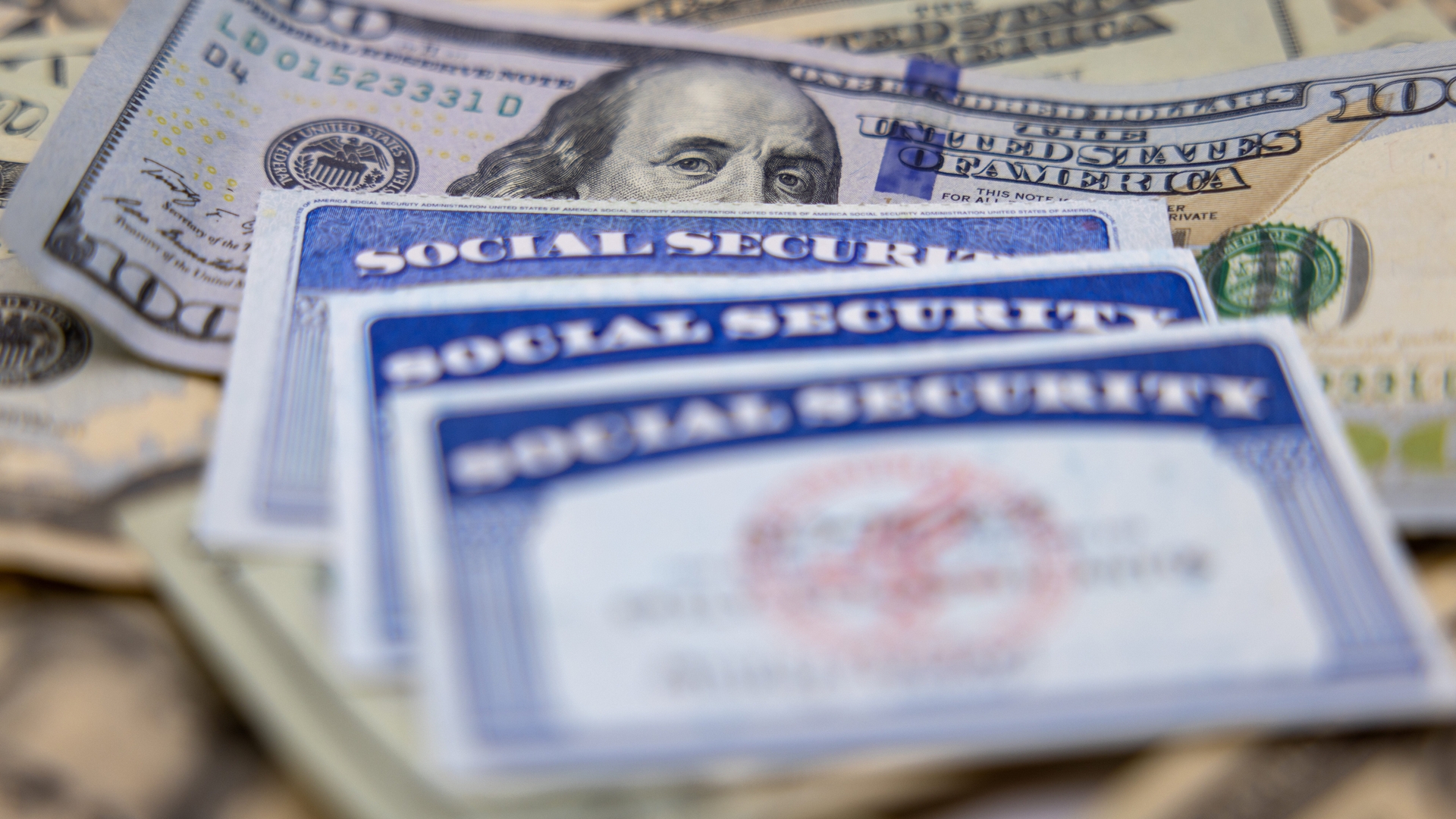 A close-up view of several Social Security cards stacked on top of dollar bills.
