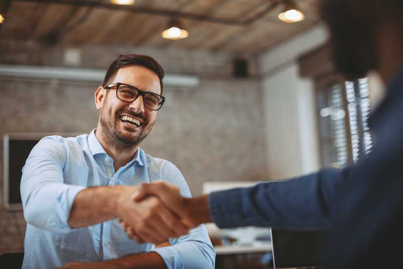 Man smiling and shaking hands in a professional setting.