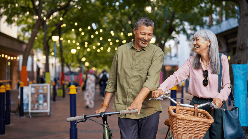 A man and a woman walking with bikes and smiling