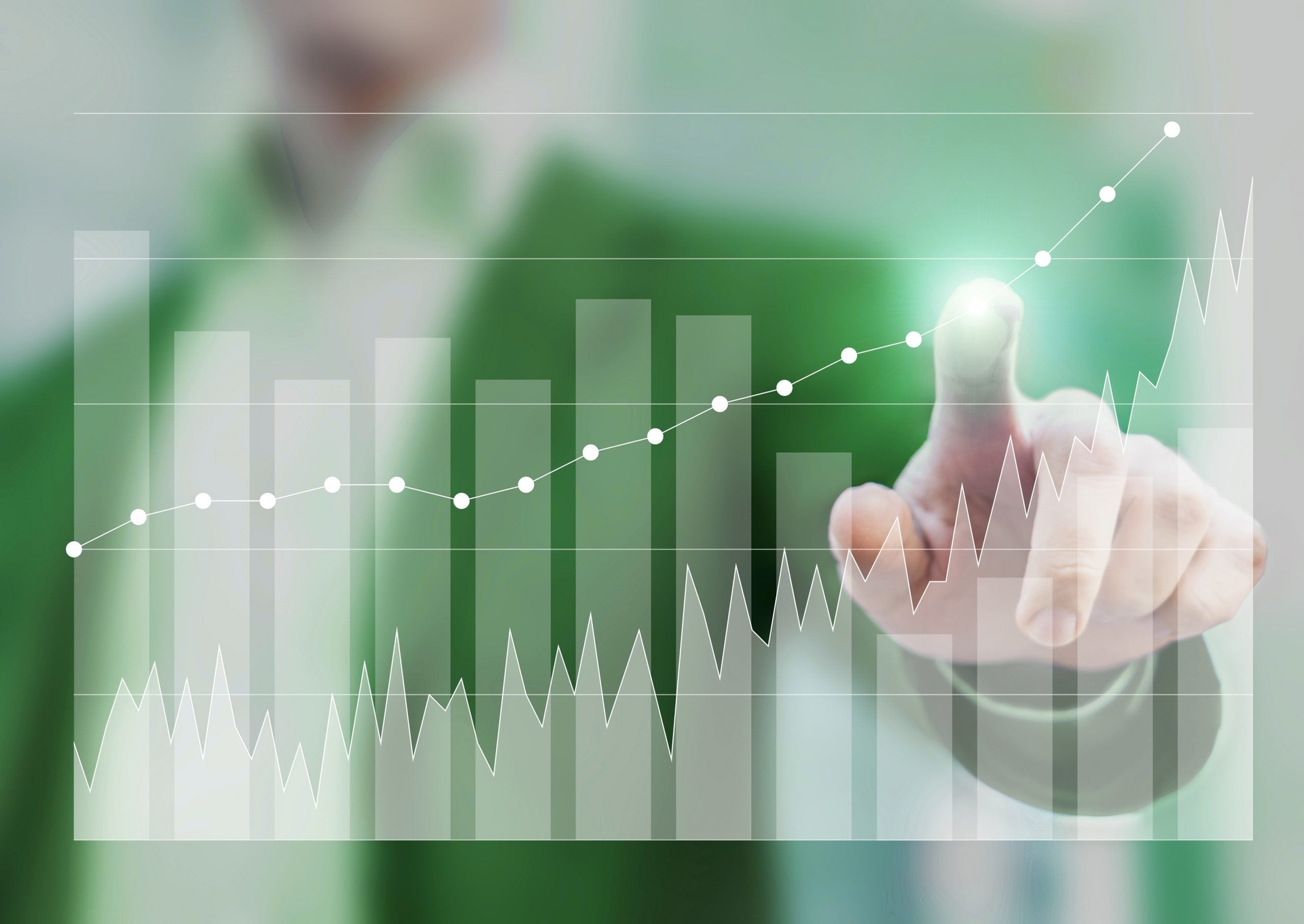 A person in a green suit points at a virtual financial graph showing upward trends with bar charts, line graphs, and data points.