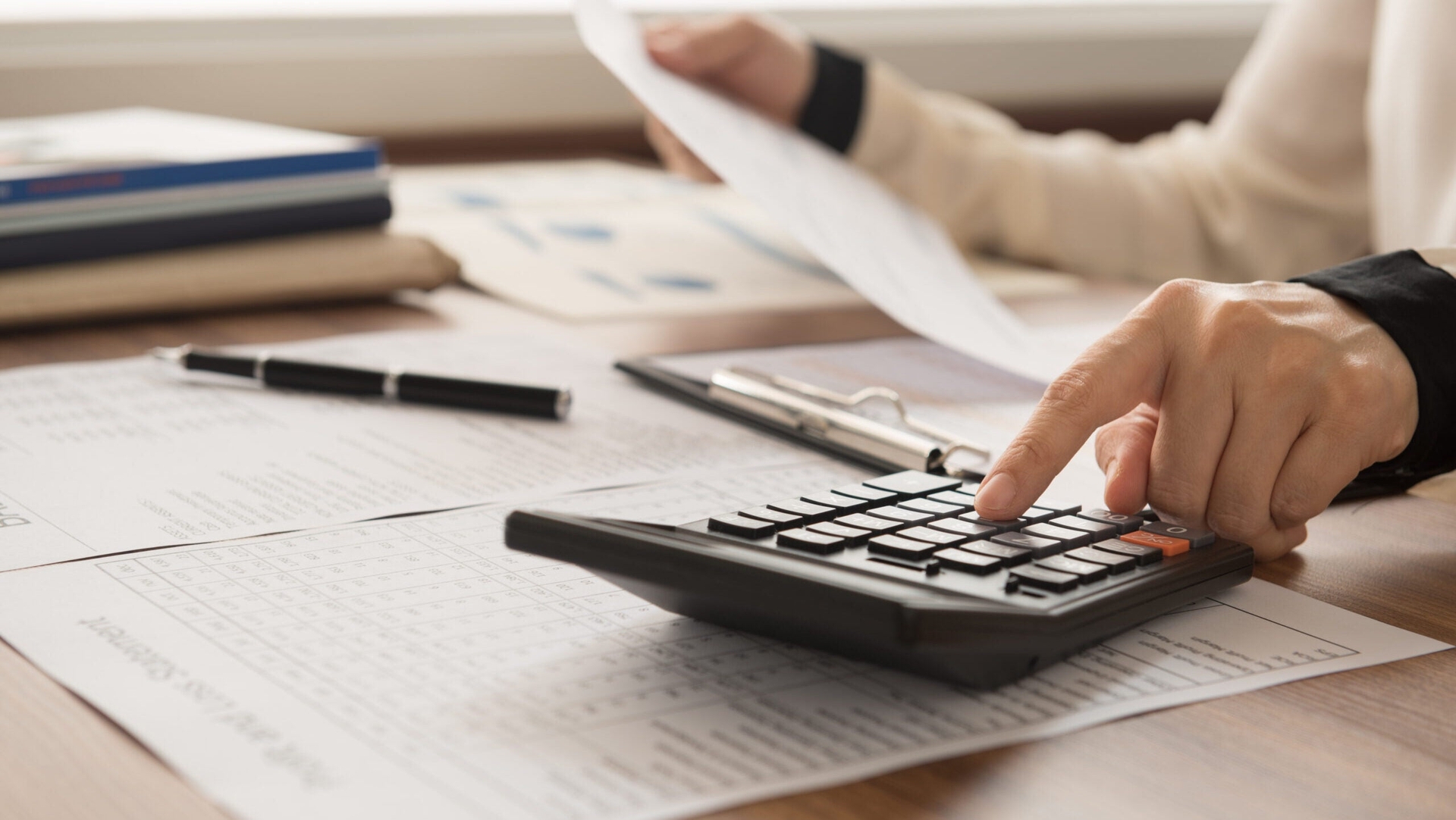 A person looks at papers and uses a calculator