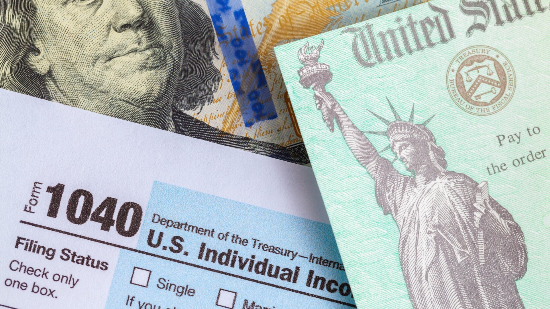 Tax Refund Check On top of Form 1040 and One Hundred Dollar Bill