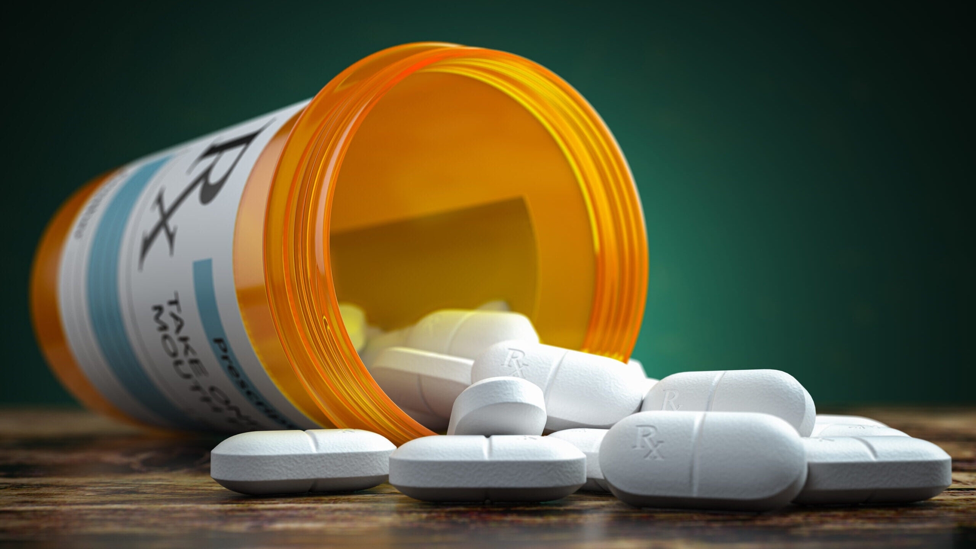 A close-up view of an orange pill bottle with white pills spilling out of it.