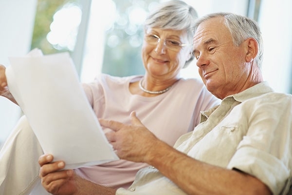 An older man and woman sitting together and reading off a piece of paper.