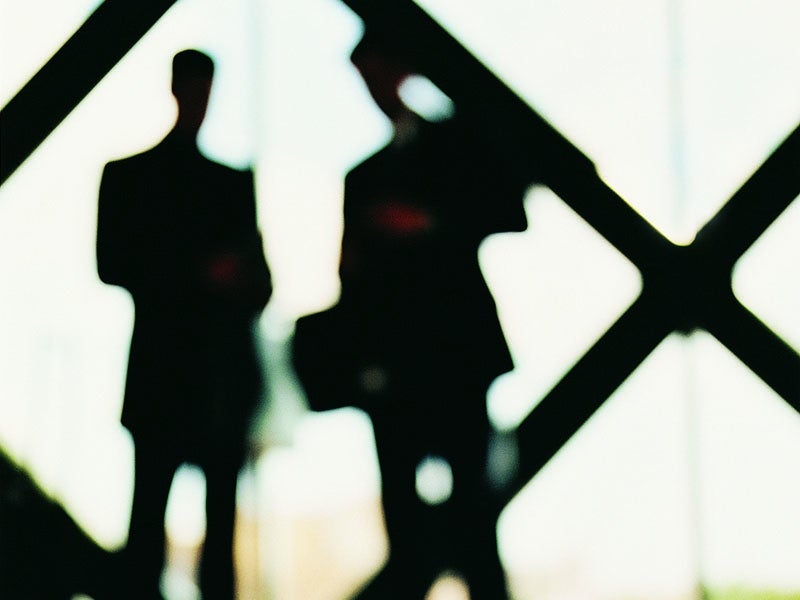 A blurred photo of two men's silhouettes in front of windows.