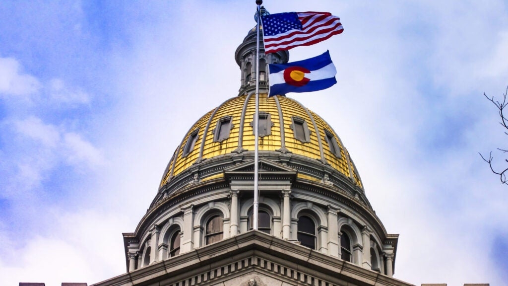 The Colorado State Capitol Building's golden dome with the American and Colorado flags waving.