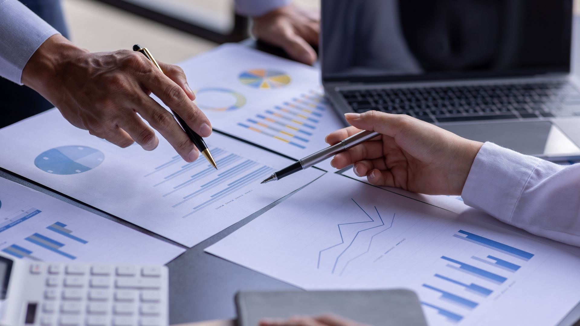 Two people looking and pointing at various financial documents.