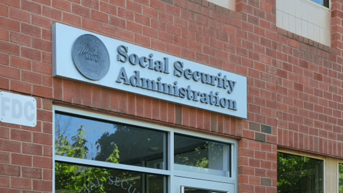 Exterior of a building with a sign reading "Social Security Administration" mounted on a brick wall above a window.